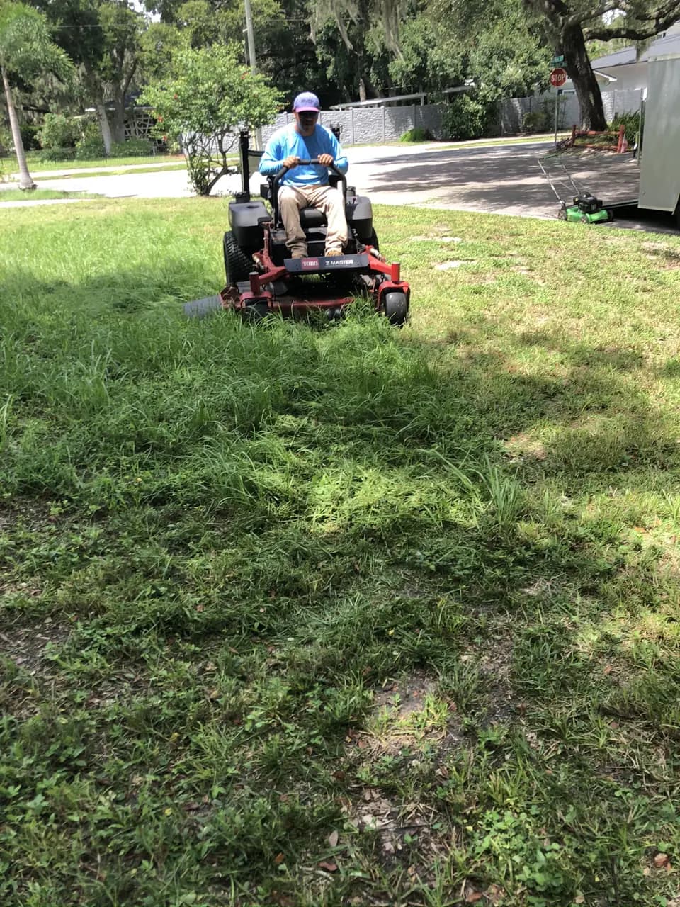 Crew member on a zero-turn mower cutting a front lawn